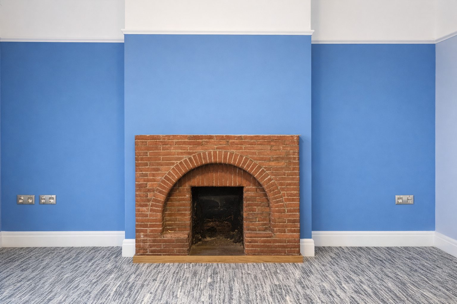 A freshly painted blue room with a brick arch fireplace