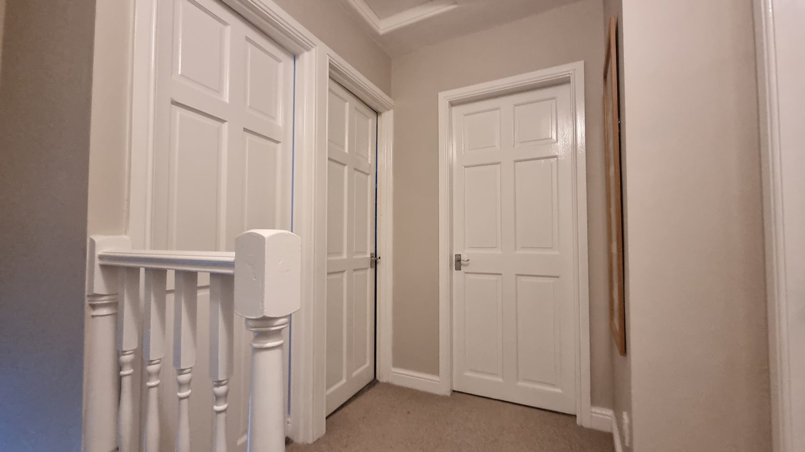 A landing with a white balustrade and freshly painted doors and woodwork