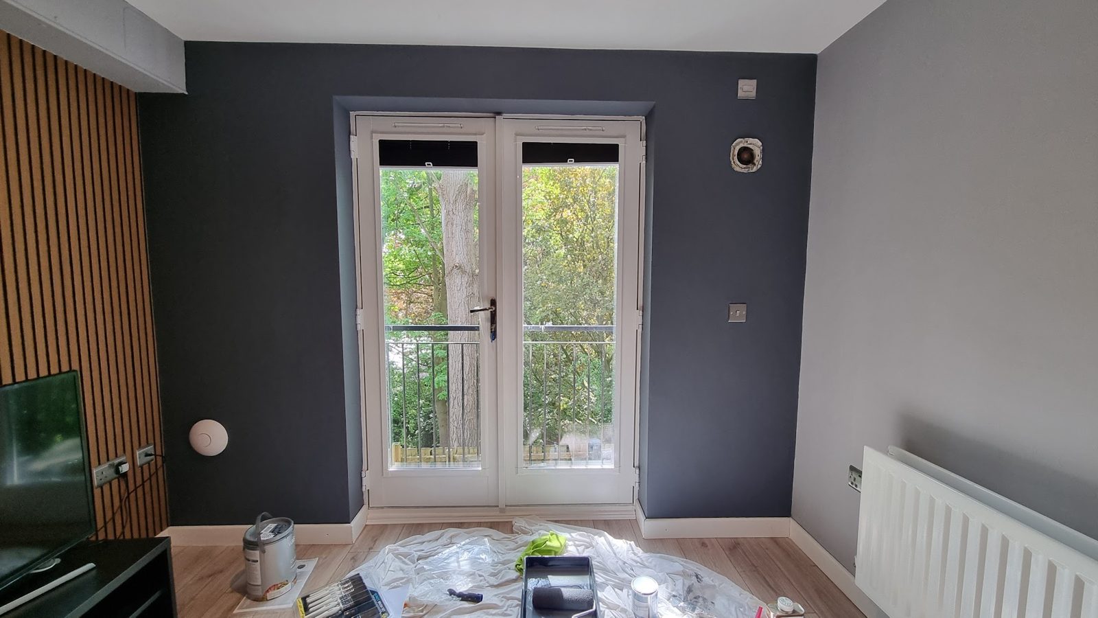 A dark grey room with a slatted wood feature wall and French doors