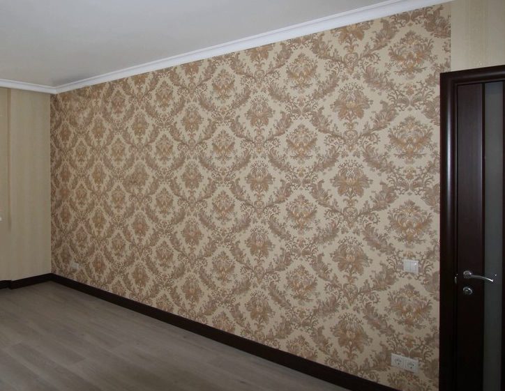 A room with a large damask pattern feature wall in cream and rose